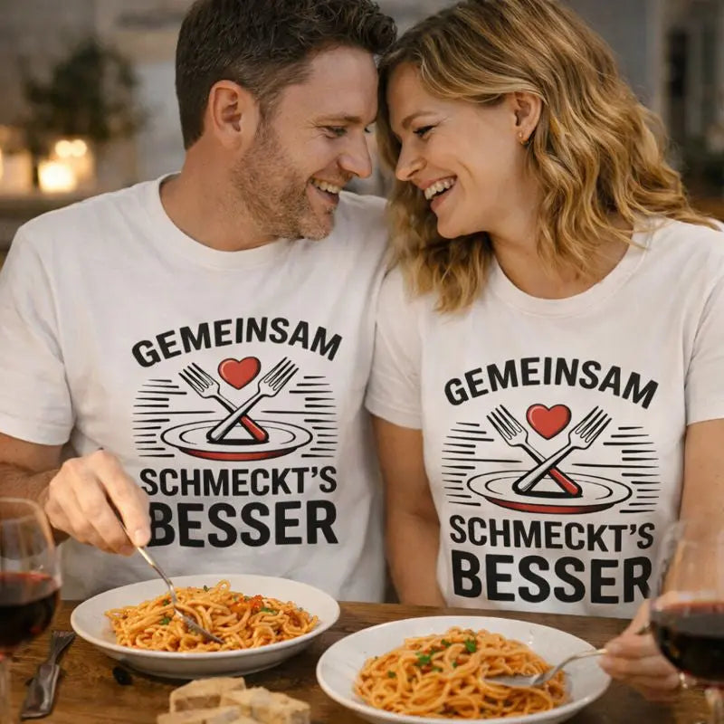 Verliebtes Paar trägt Meatware Premium T-Shirts mit dem Aufdruck „Gemeinsam schmeckt’s besser – Liebe geht durch den Magen“ beim gemeinsamen Essen, humorvolles Food- & Love-Motiv

